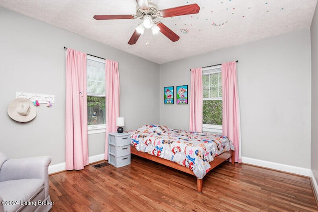 bedroom featuring hardwood / wood-style floors, ceiling fan, and a textured ceiling