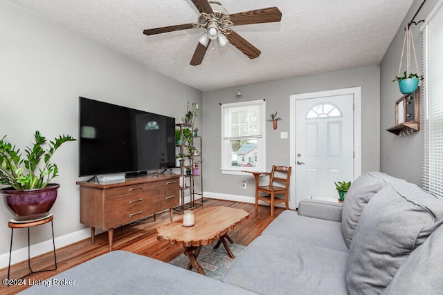 living room with a textured ceiling, hardwood / wood-style flooring, and ceiling fan