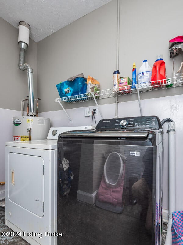 laundry room featuring water heater, a textured ceiling, and washing machine and clothes dryer