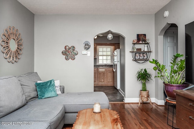 living room with dark wood-type flooring, sink, and a textured ceiling