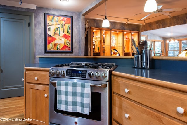 kitchen with track lighting, high end range, hanging light fixtures, hardwood / wood-style flooring, and ceiling fan