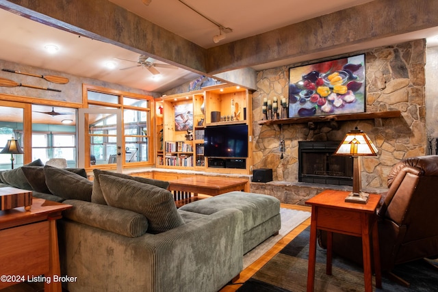 living room with a stone fireplace, vaulted ceiling with beams, hardwood / wood-style flooring, and ceiling fan