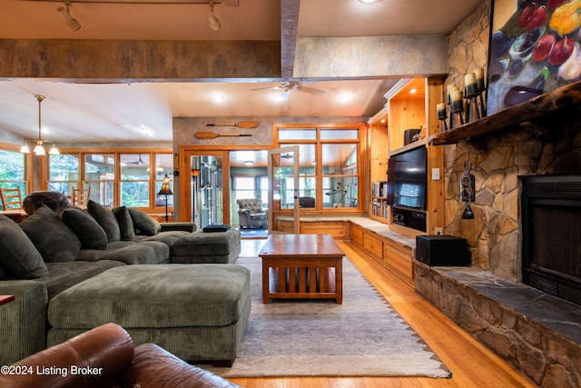 living room featuring a fireplace, plenty of natural light, light hardwood / wood-style floors, and beam ceiling