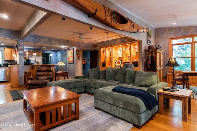 living room with beamed ceiling, ceiling fan, and light wood-type flooring