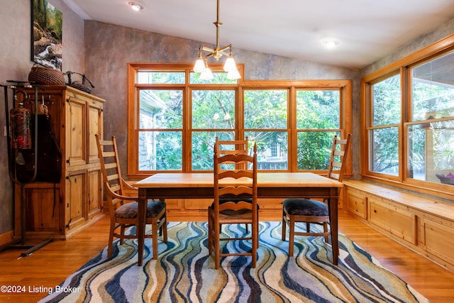 dining room featuring light wood-type flooring, an inviting chandelier, and vaulted ceiling