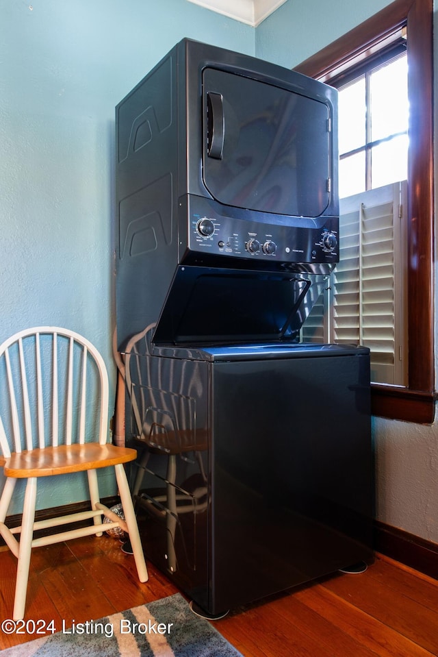 laundry room featuring stacked washer / drying machine and hardwood / wood-style flooring