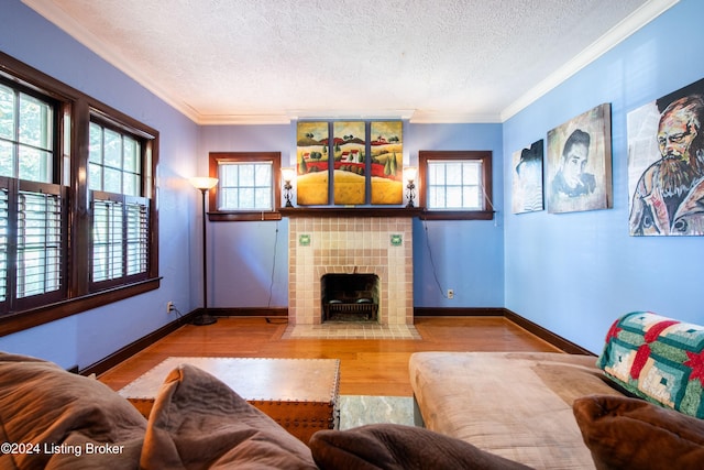 living room with light hardwood / wood-style floors, a healthy amount of sunlight, a tile fireplace, and crown molding