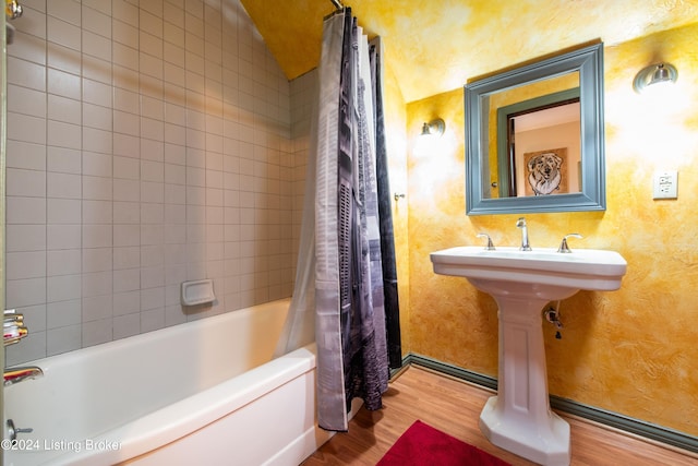 bathroom with hardwood / wood-style flooring, sink, and shower / bath combination with curtain