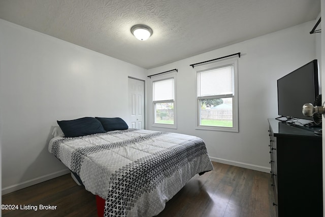 bedroom with dark wood-type flooring, a textured ceiling, and a closet