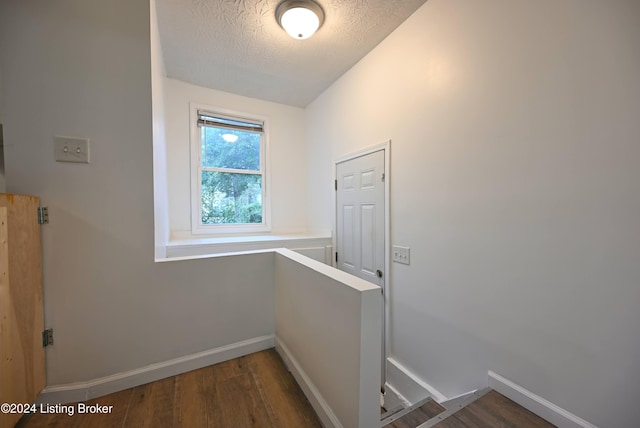 hall with dark hardwood / wood-style flooring and a textured ceiling