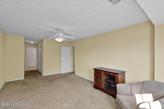 unfurnished living room featuring ceiling fan, a textured ceiling, and light carpet