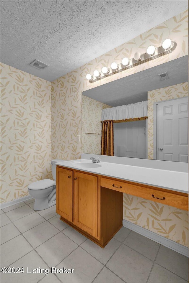 bathroom with tile patterned flooring, vanity, a textured ceiling, and toilet