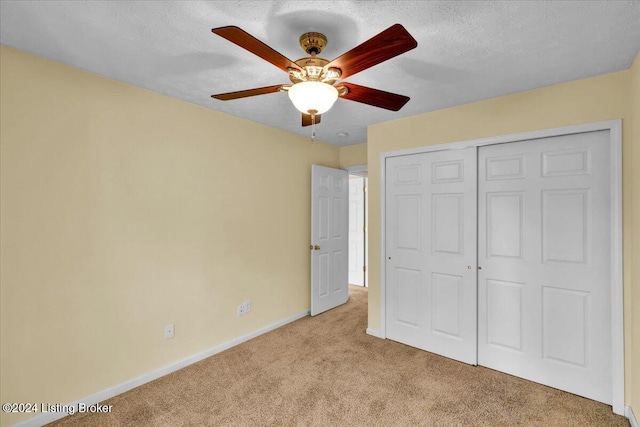 unfurnished bedroom with a textured ceiling, light carpet, ceiling fan, and a closet