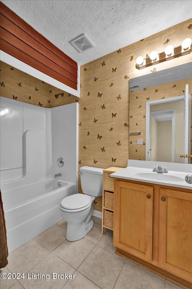 full bathroom with bathing tub / shower combination, vanity, a textured ceiling, tile patterned flooring, and toilet