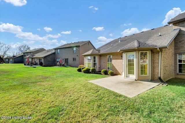 rear view of house featuring a lawn and a patio