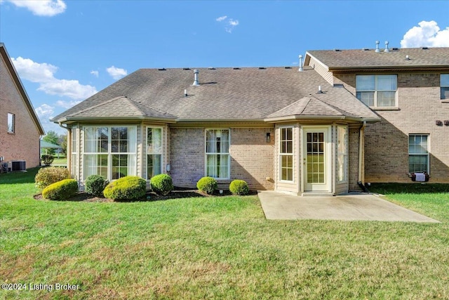 rear view of house with central AC unit, a patio, and a yard