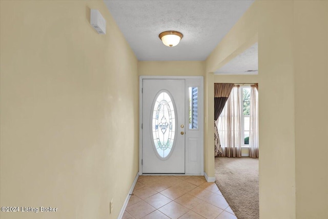 carpeted foyer with a textured ceiling