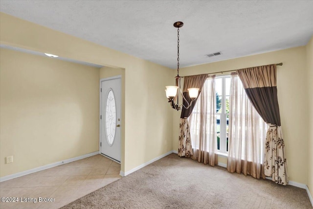 interior space featuring light colored carpet, a textured ceiling, and a notable chandelier