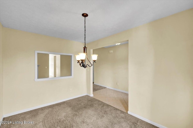 carpeted spare room featuring an inviting chandelier