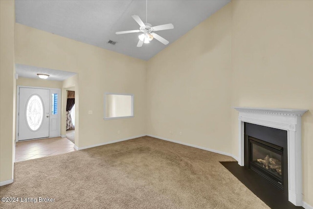 unfurnished living room featuring ceiling fan, high vaulted ceiling, and carpet