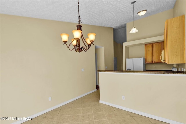 kitchen with pendant lighting, white appliances, and a textured ceiling