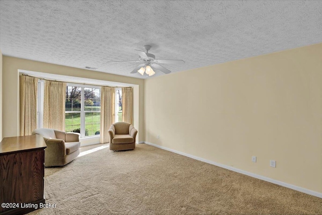 unfurnished room featuring a textured ceiling, light carpet, and ceiling fan