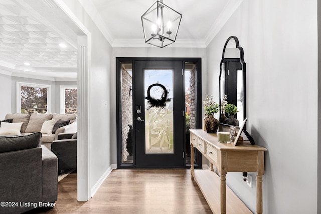 entryway with hardwood / wood-style floors, ornamental molding, and a notable chandelier