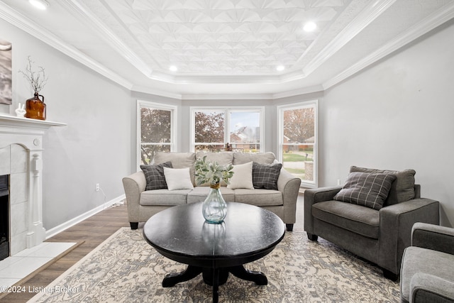 living room featuring a fireplace, hardwood / wood-style floors, a tray ceiling, and ornamental molding