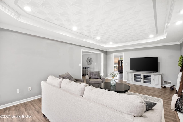 living room with a raised ceiling, crown molding, and hardwood / wood-style flooring