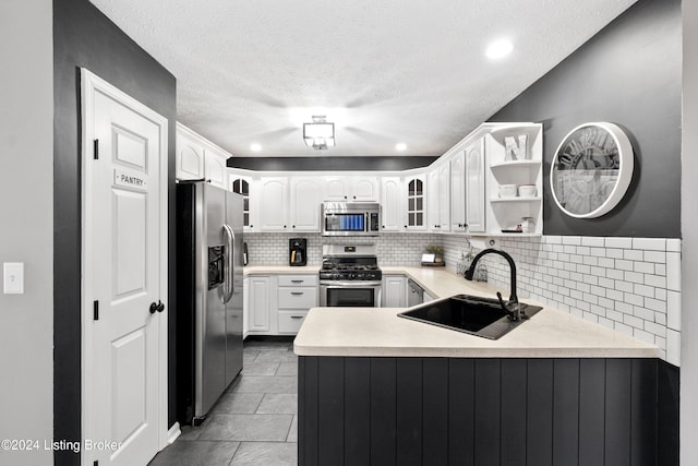 kitchen featuring sink, tasteful backsplash, kitchen peninsula, white cabinets, and appliances with stainless steel finishes