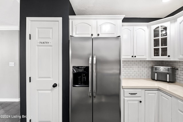 kitchen with white cabinets, stainless steel fridge with ice dispenser, a textured ceiling, and tasteful backsplash