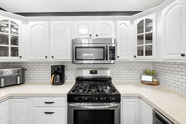 kitchen with white cabinets, appliances with stainless steel finishes, and tasteful backsplash