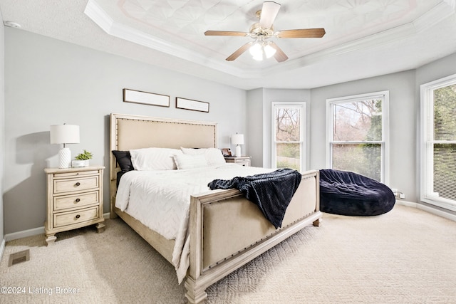 bedroom with a tray ceiling, ceiling fan, crown molding, and light colored carpet