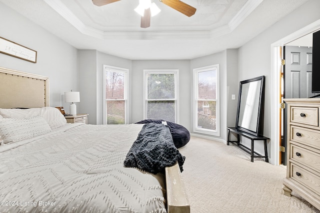 carpeted bedroom featuring a tray ceiling, ceiling fan, and crown molding