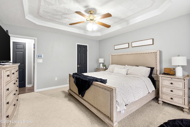 carpeted bedroom featuring a tray ceiling, ceiling fan, and crown molding