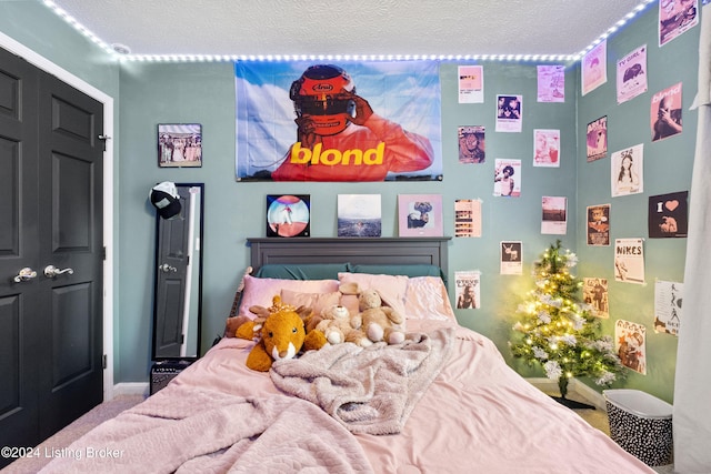 carpeted bedroom with a textured ceiling and a closet