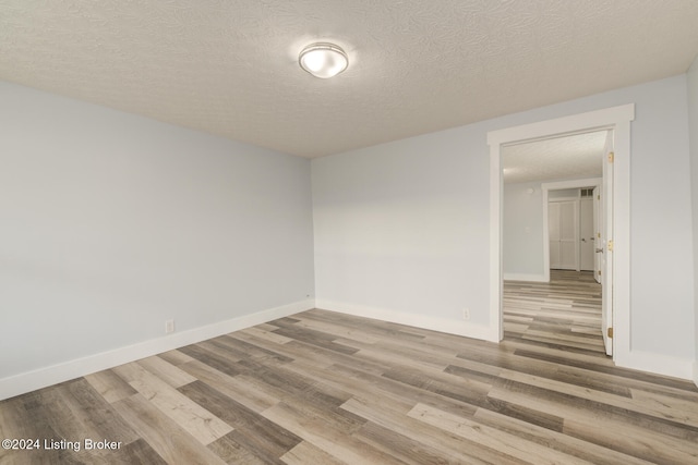 unfurnished room with wood-type flooring and a textured ceiling