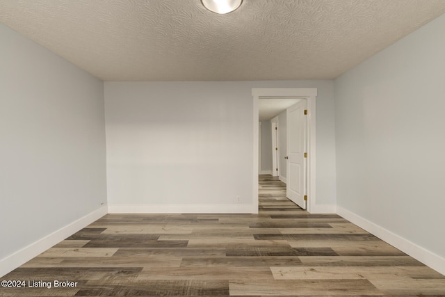 empty room with a textured ceiling and dark hardwood / wood-style flooring