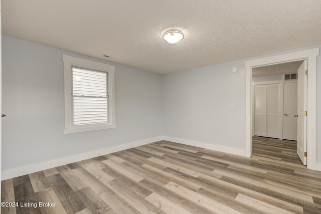 spare room featuring light hardwood / wood-style floors and a textured ceiling