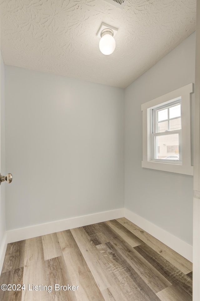 spare room with a textured ceiling and hardwood / wood-style flooring