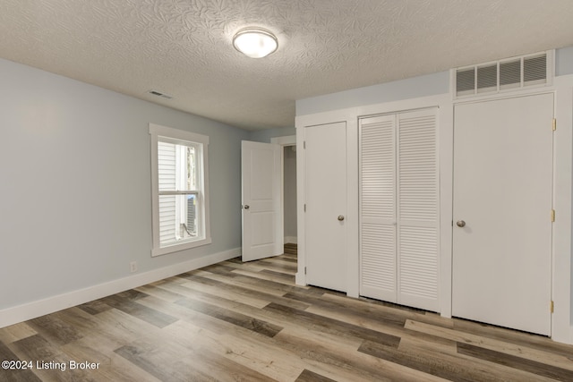 unfurnished bedroom with light wood-type flooring and a textured ceiling