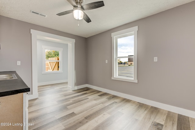 unfurnished dining area with light hardwood / wood-style floors, ceiling fan, a textured ceiling, and sink