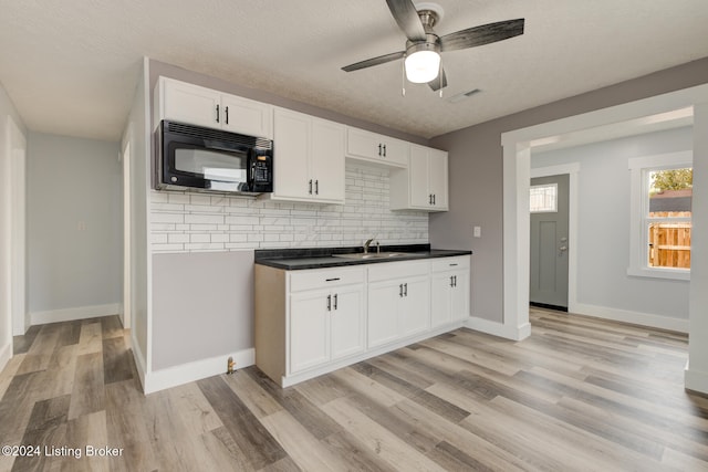 kitchen featuring white cabinetry, decorative backsplash, light hardwood / wood-style flooring, and a textured ceiling