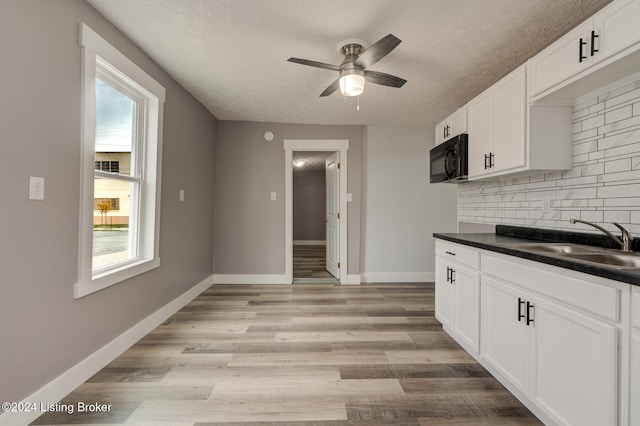 kitchen featuring white cabinetry, light wood-type flooring, a textured ceiling, sink, and decorative backsplash