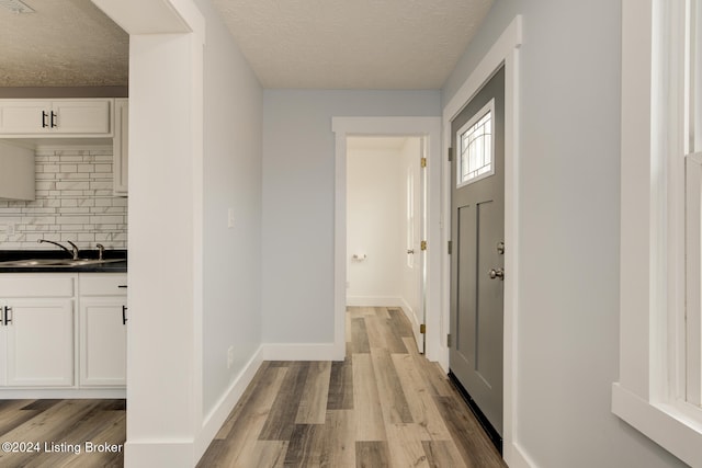 interior space featuring light wood-type flooring, sink, and a textured ceiling