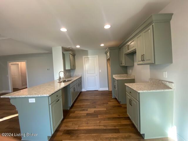 kitchen featuring sink, kitchen peninsula, a kitchen breakfast bar, light stone countertops, and dark wood-type flooring