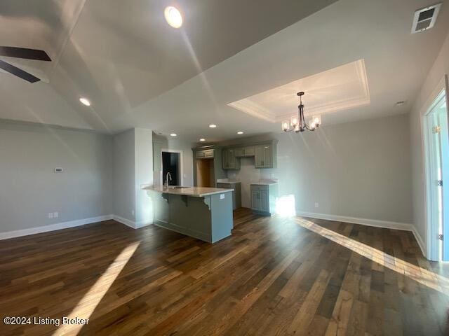 kitchen featuring sink, kitchen peninsula, hanging light fixtures, a raised ceiling, and dark wood-type flooring