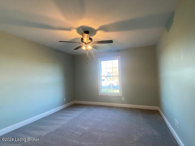 unfurnished room with ceiling fan and dark carpet