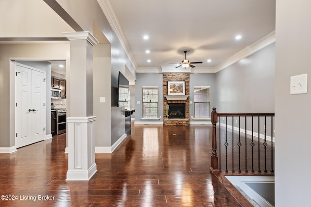 unfurnished living room featuring ornamental molding, a fireplace, dark hardwood / wood-style floors, decorative columns, and ceiling fan