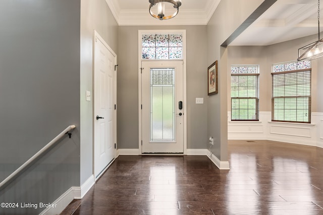 entrance foyer featuring ornamental molding, dark hardwood / wood-style floors, and an inviting chandelier